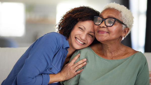 Two women smile and embrace one another.