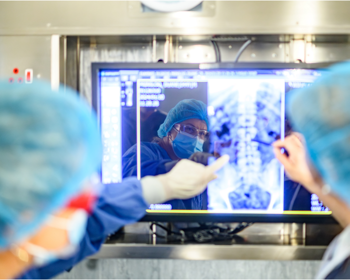 Medical professionals inspect an x-ray of a patient's spine.