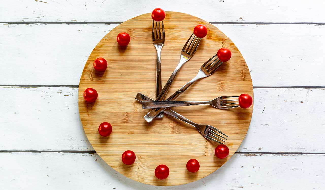 A plate with forks and tomatoes decorated like a clockface.