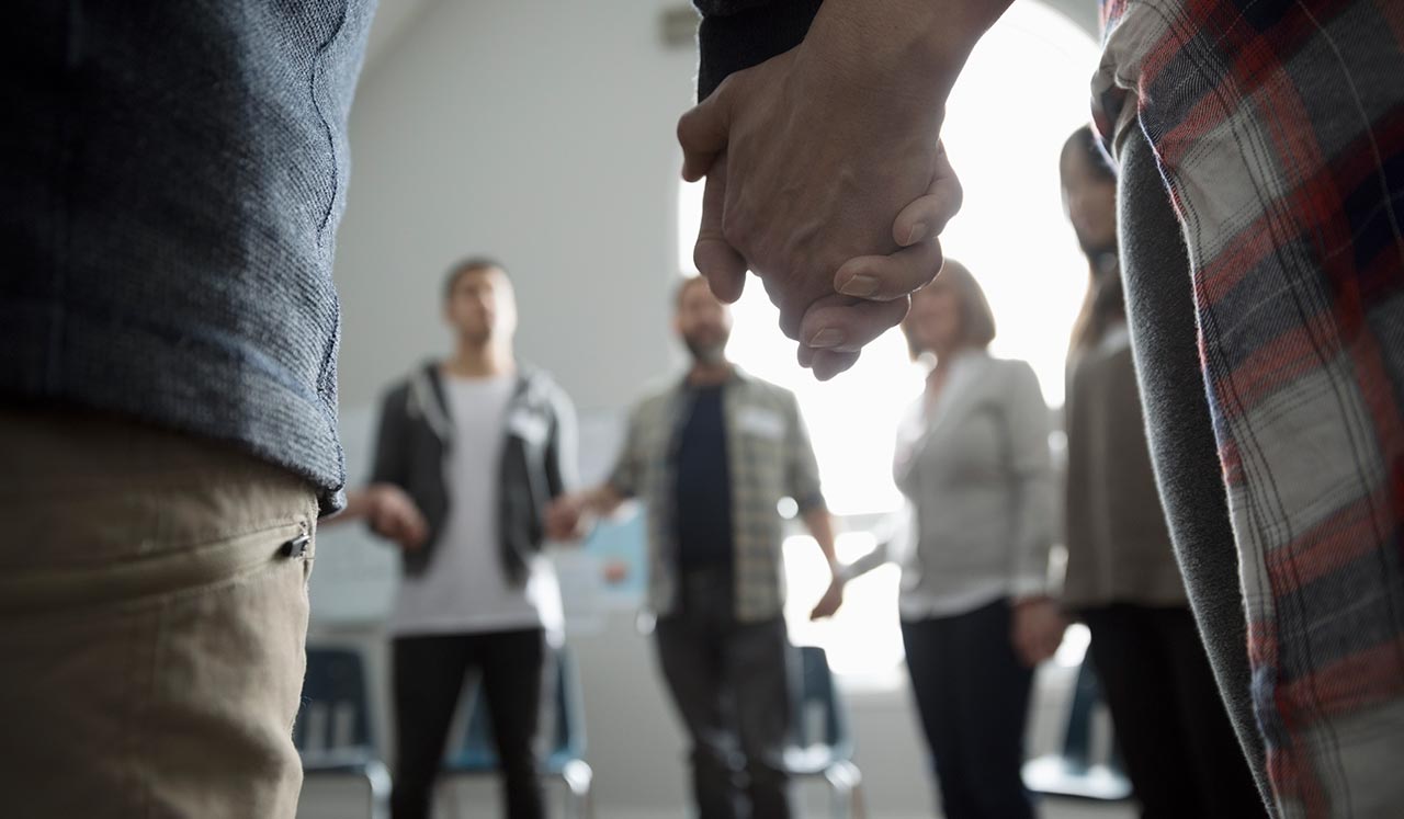 A circle of people holding hands as if in a support group.