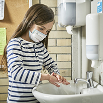 A child in a school setting washing their hands.