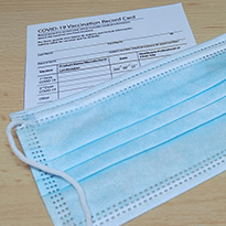 A vaccination record card and face mask on a table.