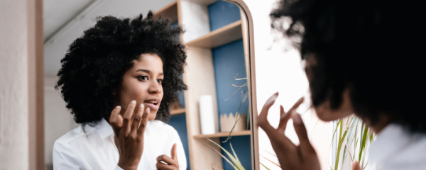 A woman looking in the mirror and practicing self-care