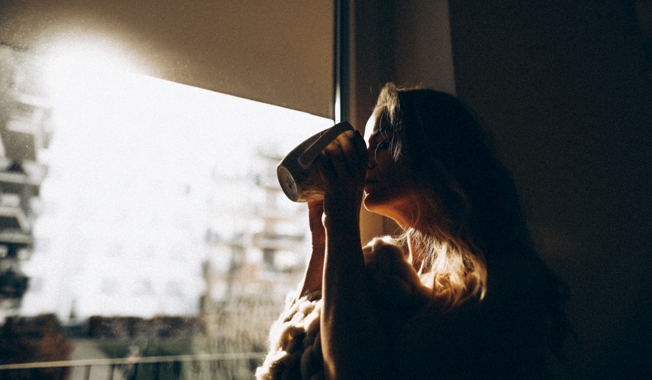 Woman drinking coffee near a window
