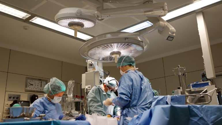 Three physicians stand in an operating room.