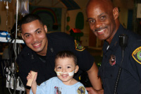 Pediatric patient poses with HPD officers
