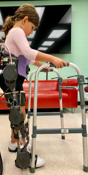 A young girl uses assistive technology to walk at TIRR Memorial Hermann.