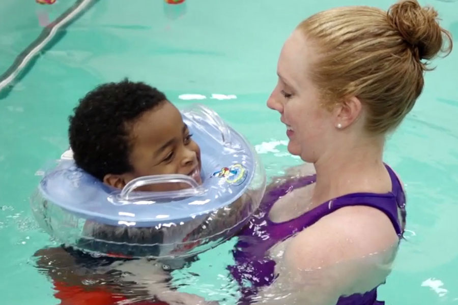 Child swimming in a pool with therapist