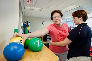 Woman lifting weighted balls for rehabilitation