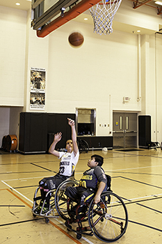 Two boys in wheelchair playing basketball