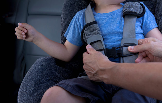 Adult buckling a child into a car seat