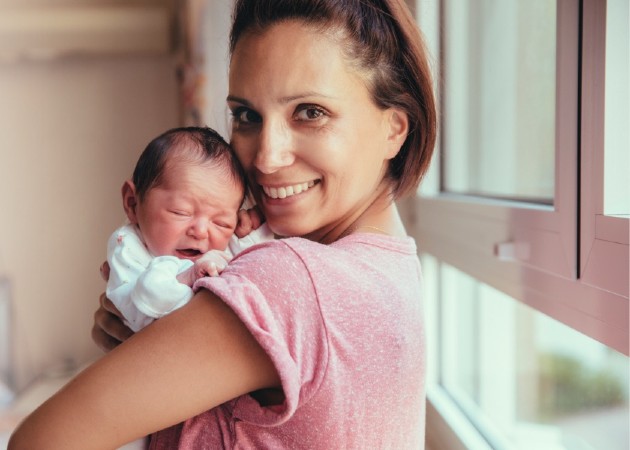 Mother smiling while holding newborn