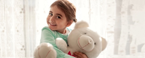 Little girl squeezing teddy bear