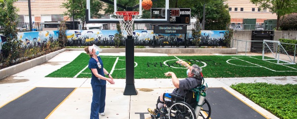 Therapist and patient playing basketball in the sports park as part of therapy