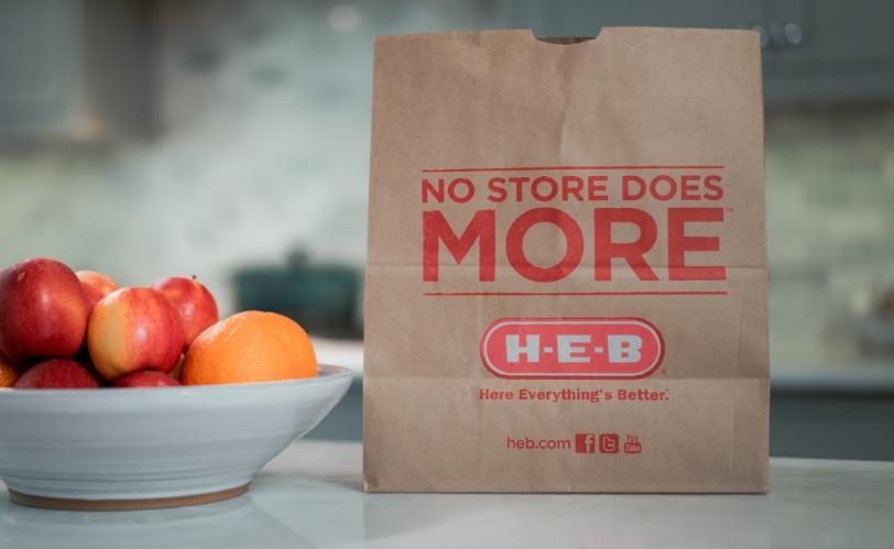 HEB grocery bag next to bowl of fruit