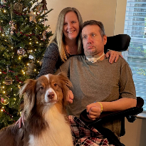 Eric Smith, a TIRR Memorial Hermann patient, sits with his wife and dog in front of a Christmas tree.